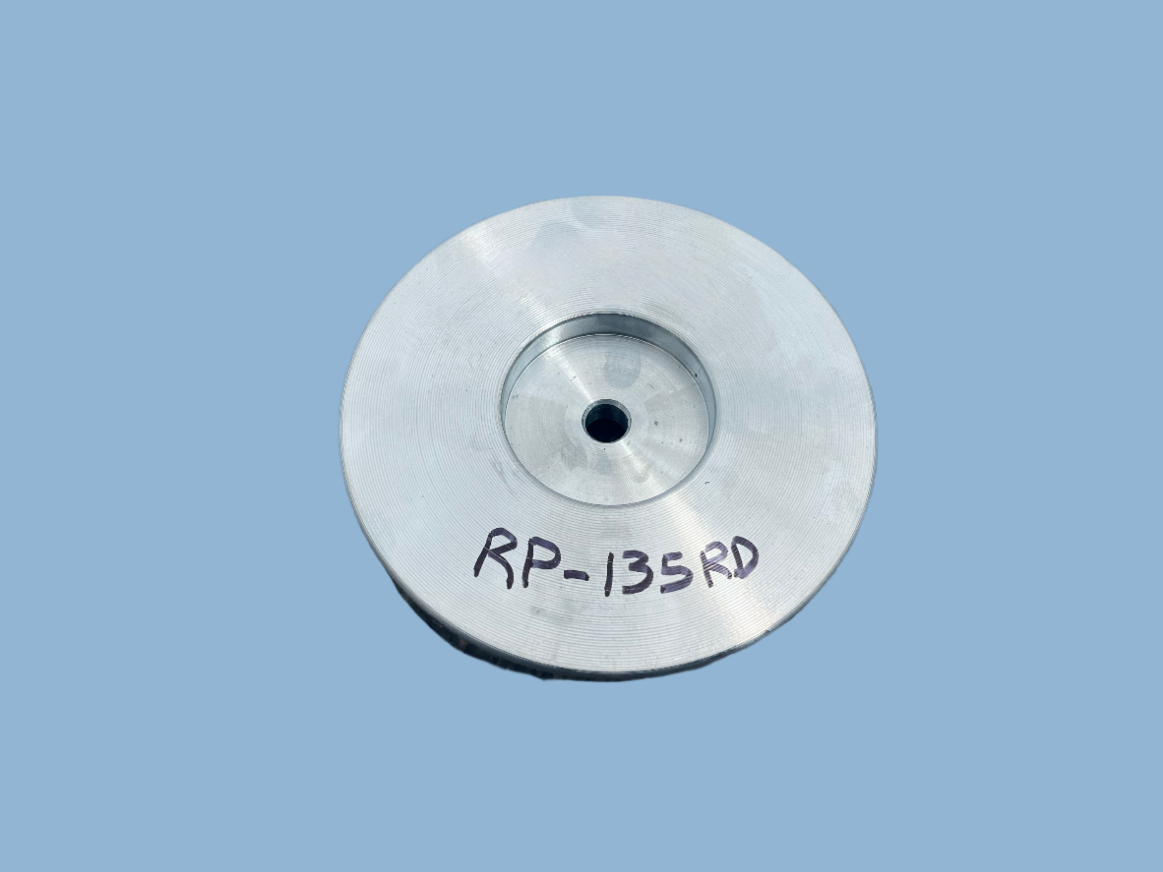 Metallic object with 'RP-135RD' marking on a textured surface